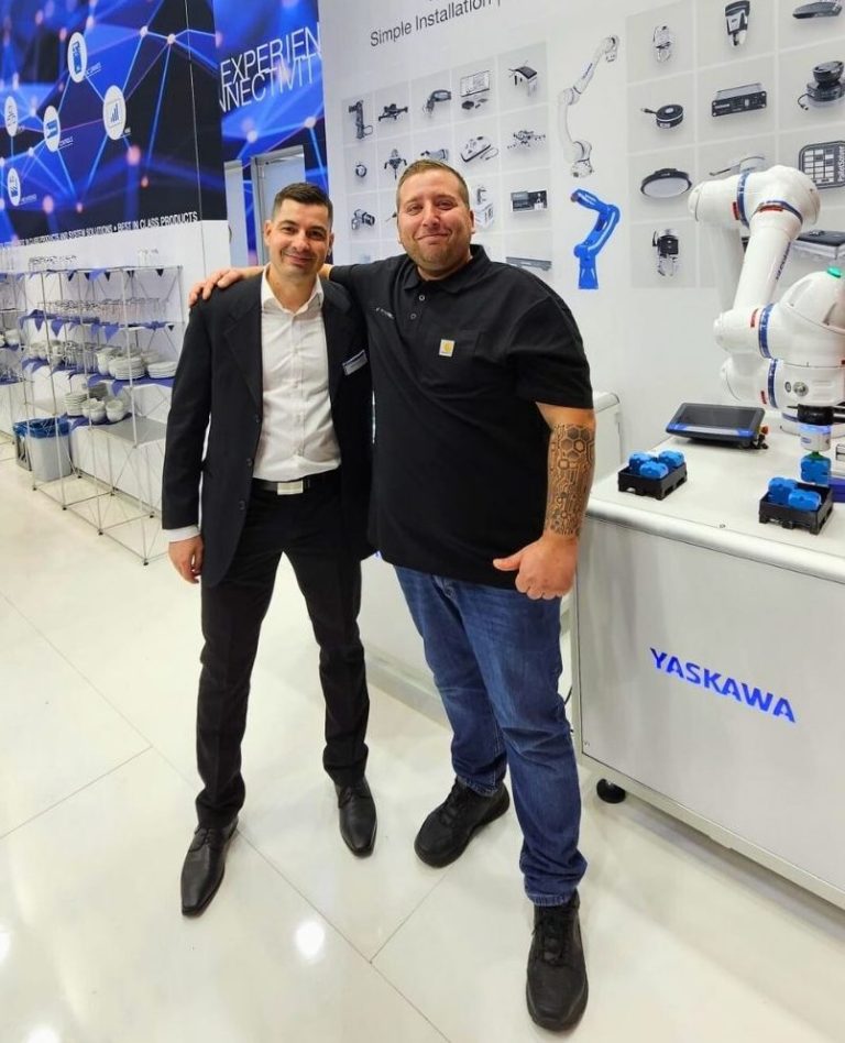 Yaskawa und Revobotics auf der SPS Messe 2024 Zwei Männer stehen in einem modernen Ausstellungsraum mit technischen Geräten.